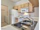 Functional kitchen featuring light wood cabinets, white appliances, and adjacent laundry area at 16013 S Desert Foothills Pkwy # 2130, Phoenix, AZ 85048