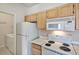 Efficient kitchen features wood cabinets, white appliances, and adjacent laundry area at 16013 S Desert Foothills Pkwy # 2130, Phoenix, AZ 85048