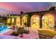 Stunning backyard with lush landscaping, stone patio, and beautiful arched doorways at twilight at 16469 N 113Th Way, Scottsdale, AZ 85255