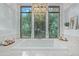 Bright bathroom with marble tile, a soaking tub, a chandelier, and a large window with a backyard view at 16469 N 113Th Way, Scottsdale, AZ 85255