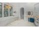 A bright bathroom featuring a soaking tub under a chandelier, marble tile, and a vanity with multiple mirrors at 16469 N 113Th Way, Scottsdale, AZ 85255