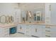 A bright bathroom featuring double sinks, custom white cabinets, gold fixtures, and marble countertops and wall paneling at 16469 N 113Th Way, Scottsdale, AZ 85255