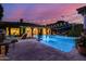 Inviting pool area with string lights, lush greenery, and mountain views at twilight at 16469 N 113Th Way, Scottsdale, AZ 85255
