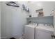 Well-lit laundry room equipped with a washer, dryer, and shelving for storage at 17981 W Agave Rd, Goodyear, AZ 85338
