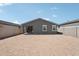 A dirt-filled backyard with gray exterior, block fences, and a view of neighboring houses at 18256 W La Senda Dr, Surprise, AZ 85387
