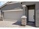 Welcoming home entrance featuring a two-car garage, stone accents, and a sleek front door for a modern touch at 18256 W La Senda Dr, Surprise, AZ 85387