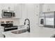 Modern kitchen island with dark faucet and sink plus stainless steel microwave and stove at 18256 W La Senda Dr, Surprise, AZ 85387