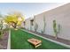 Spacious backyard with an artificial turf lawn, mature trees, and a fun cornhole game area at 20 W Canterbury Ln, Phoenix, AZ 85023