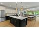Bright open-concept kitchen with sleek black and white cabinetry and large island leading to a dining/living area and outdoor pool at 20483 E Mockingbird Dr, Queen Creek, AZ 85142