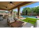 An outdoor patio featuring lounge seating, a swimming pool, an outdoor kitchen, and well-manicured landscaping at 20483 E Mockingbird Dr, Queen Creek, AZ 85142