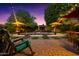 Inviting backyard pool area with mature landscaping, brick patio, and comfortable seating under festive string lights at dusk at 2066 E Lockwood St, Mesa, AZ 85213