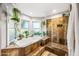 Spa-like bathroom featuring a soaking tub, stone-tiled shower, and bright natural light at 2066 E Lockwood St, Mesa, AZ 85213