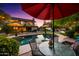 Sparkling pool surrounded by lush landscaping, patio furniture, and ambient lighting for ultimate relaxation at 2066 E Lockwood St, Mesa, AZ 85213