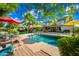 Beautiful backyard with a sparkling pool, mature palm trees, patio furniture and sunny yellow and red umbrellas at 2066 E Lockwood St, Mesa, AZ 85213