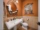Charming powder room featuring a pedestal sink, decorative mirror, and tiled walls at 20791 W Main St, Buckeye, AZ 85396
