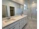 Bright bathroom featuring a double sink vanity with white cabinets and a glass-enclosed shower at 25354 W Bowker St, Buckeye, AZ 85326