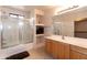 Bright bathroom featuring a glass-enclosed shower-tub combo, single sink vanity, and linen shelves at 2749 S Powell Rd, Apache Junction, AZ 85119