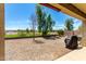 View of a spacious backyard with gravel, patio, and partial view of a green space and blue skies at 28259 N Chalcocite St, San Tan Valley, AZ 85143