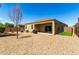 A view of the backyard with a covered patio, gravel, small grass area, and view of the exterior of the home at 28259 N Chalcocite St, San Tan Valley, AZ 85143