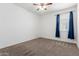 Cozy bedroom featuring neutral carpet, ceiling fan, and window with blue curtains at 28259 N Chalcocite St, San Tan Valley, AZ 85143