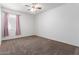 Neutral-toned carpeted bedroom with a ceiling fan and window with pink curtains at 28259 N Chalcocite St, San Tan Valley, AZ 85143
