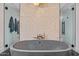 Close-up of a stylish freestanding tub with a decorative tile accent wall and dual shower entrances at 3425 N 50Th Pl, Phoenix, AZ 85018