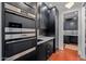Gourmet kitchen featuring stainless steel Wolf ovens, modern black cabinets, and red tile flooring at 3425 N 50Th Pl, Phoenix, AZ 85018