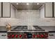 Stainless steel Wolf gas range with white brick backsplash and stainless vent hood, perfect for cooking enthusiasts at 3425 N 50Th Pl, Phoenix, AZ 85018