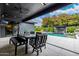 Covered patio dining area with views of the pool, outdoor kitchen, and lush landscaping, perfect for alfresco dining at 3425 N 50Th Pl, Phoenix, AZ 85018