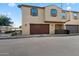 View of the townhome featuring a private garage, neutral stucco, and coordinated brown trim at 3855 S Mcqueen Rd # 101, Chandler, AZ 85286