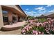 An inviting outdoor living space featuring a covered patio with seating surrounded by lush, mature landscaping and beautiful pink flowers at 3928 N 151St Ave, Goodyear, AZ 85395