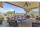 Inviting covered patio with ample seating, ceiling fan, and beautifully pavers overlooking the desert landscape at 44284 W Buckhorn Trl, Maricopa, AZ 85138