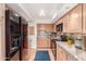 Bright kitchen with wood cabinets, granite countertops, and stainless steel appliances, featuring red tiled flooring at 5102 N 31St Pl # 436, Phoenix, AZ 85016