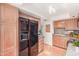 Kitchen with wood cabinets, black refrigerator with water dispenser, complemented by red tiled flooring at 5102 N 31St Pl # 436, Phoenix, AZ 85016