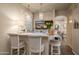 Wet bar area with stone countertop, barstool seating, pendant lighting and adjacent view into formal dining area at 7425 E Gainey Ranch Rd # 13, Scottsdale, AZ 85258