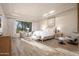 Bright bedroom with wood-look tile, tray ceiling, decorative wall art, seating, and large window at 7425 E Gainey Ranch Rd # 13, Scottsdale, AZ 85258