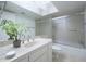 Bright bathroom with a skylight features a shower over tub with glass doors, and a decorative plant on the countertop at 7816 N 47Th St, Paradise Valley, AZ 85253