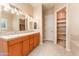Bathroom featuring double sinks with tile countertops, a large mirror, and access to the tub and closet at 7969 S 172Nd St, Queen Creek, AZ 85142