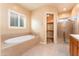 Bathroom features an oval bathtub, shower, large shuttered window, and a door to a walk-in closet at 7969 S 172Nd St, Queen Creek, AZ 85142