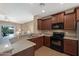 Well-lit kitchen featuring stone countertops, dark wood cabinets, and an open view to the living area at 799 W Press Rd, San Tan Valley, AZ 85140
