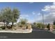 Gated community entrance featuring stone pillars, desert landscaping, and a tree on a sunny day at 11934 S 181St Ave, Goodyear, AZ 85338