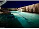 Inviting pool with small waterfall feature and desert landscaping, illuminated at night for a relaxing ambiance at 11934 S 181St Ave, Goodyear, AZ 85338
