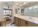 Elegant bathroom featuring double sinks, a large mirror, wooden cabinets, and a glimpse into the bedroom at 22849 E Marsh Rd, Queen Creek, AZ 85142