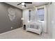 Bedroom showcases neutral decor, a dream catcher, woven shades, and white wooden crib with mobile at 22849 E Marsh Rd, Queen Creek, AZ 85142