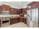 Gourmet kitchen featuring stainless steel appliances, dark wood cabinets and stone countertops at 2701 E Caldwell St, Phoenix, AZ 85042