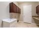 Well-lit laundry room features a large sink, tile flooring, and built-in cabinetry at 2701 E Caldwell St, Phoenix, AZ 85042