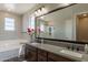 Bathroom featuring a double sink vanity, soaking tub, walk-in shower, and large mirror at 3871 E Harrison St, Gilbert, AZ 85295
