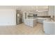 Kitchen with stainless steel refrigerator, tile floor and island with marble countertop at 43601 W Cowpath Rd, Maricopa, AZ 85138