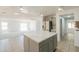 Open kitchen with center island and marble countertops looks into a carpeted living area at 43601 W Cowpath Rd, Maricopa, AZ 85138