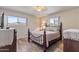 Cozy bedroom with rustic wood floors, decorative wrought iron bed frame, and natural light from two windows at 6631 E Dallas St, Mesa, AZ 85205